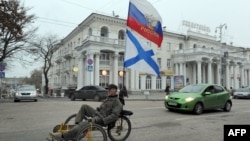 Проруски активист со руско знаме вози велосипед во Севастопол, град во Украина