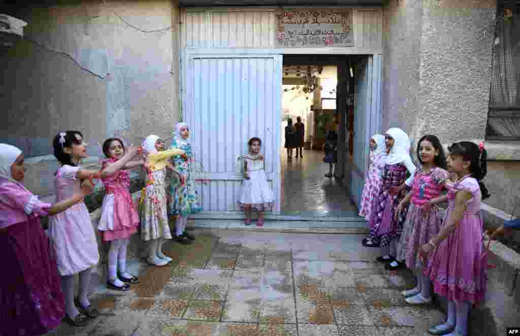 Syrian schoolgirls stand at the entrance of the Saif al-Dawla school as they take part in activities surrounding an art competition organized as part of a local initiative to shift the children's minds from the atrocities of the Syrian war, in the besieged rebel bastion of Douma. (AFP/Abd Doumany)