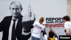 "Доза доцу репортераш" плакат дIатухуш бу, Путин Владимиран сурт а долуш. Путина гойту жест символ ю цо маьрша пресса лараран