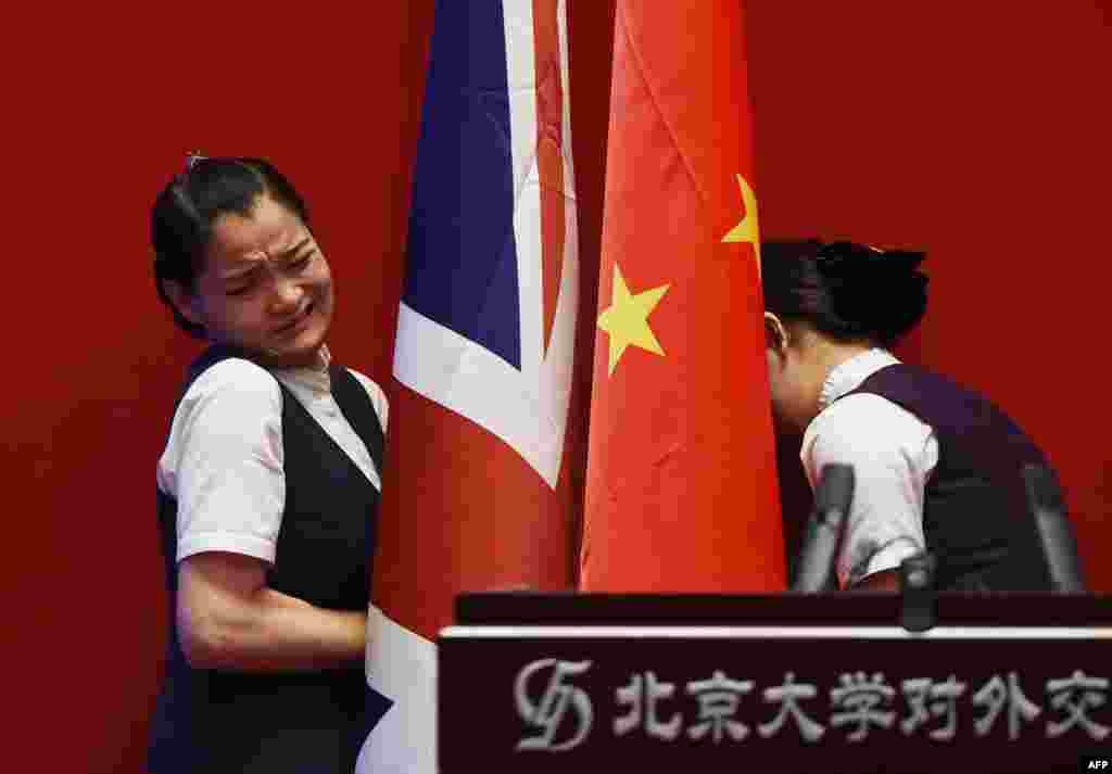 Two attendants install British and Chinese flags behind the podium before a speech by Britain's Foreign Secretary Philip Hammond to students at Peking University in Beijing on August 12. (AFP/Greg Baker)