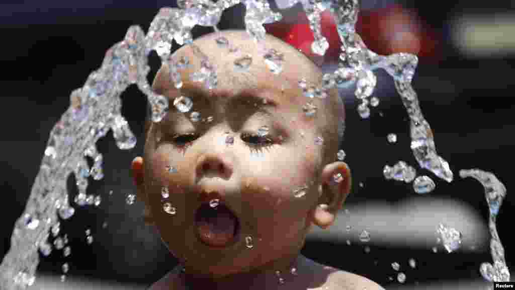 A Filipino boy cools off with water from a hose on a hot day in Manila on April 24. (Reuters/Cheryl Ravelo)