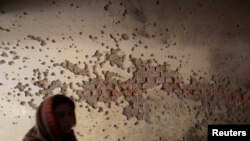 A local reporter walks past a damaged wall of the Army Public School, which was attacked by Taliban gunmen in Peshawar on December 16.