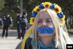 Молодая женщина с заклеенным ртом участвует в проукраинской акции протеста в Симферополе. 13 марта 2014 года.