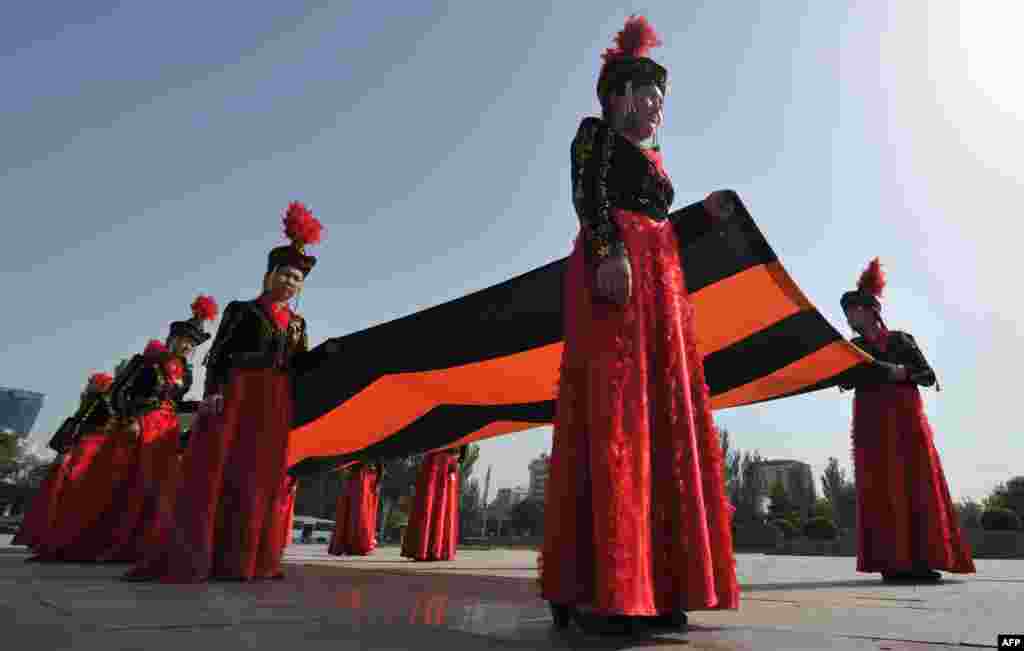 Wearing their traditional costumes, young Kyrgyz women carry a huge St. George's ribbon, a military valor symbol of both Imperial Russia and the Soviet Union, during a ceremony marking the upcoming Victory Day in Bishkek on May 7. (AFP/Vyacheslav Oseledko)