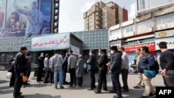 People wait in line to receive packages for precautions against the coronavirus from a booth in Tehran on March 15.