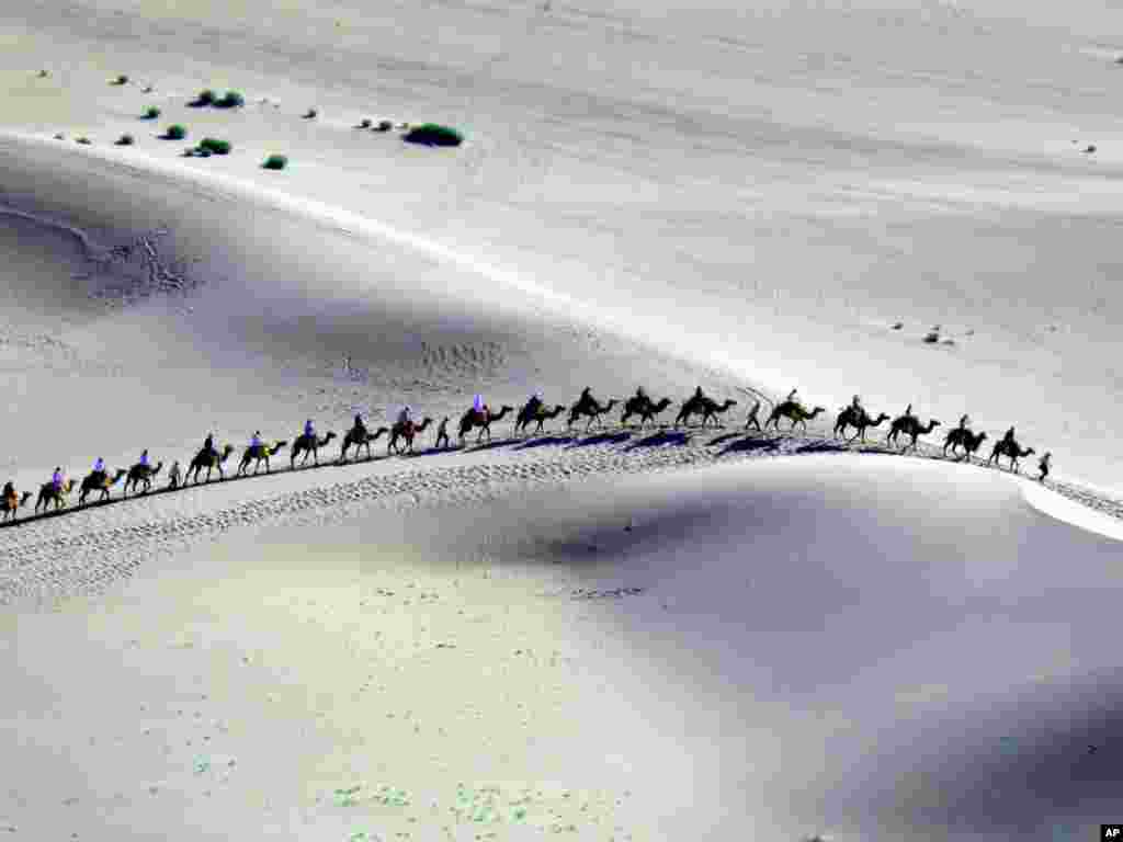 Туристы на верблюдах в горах Мингша в провинции Ганьсу. - Во время традиционного фестиваля корабля Китайского дракона, много туристов шли по горам "Певучего Песка" (Мингша Шань) в провинции Ганьсу на северо-западе Китая. Фото Zhang Weixian для AP. 