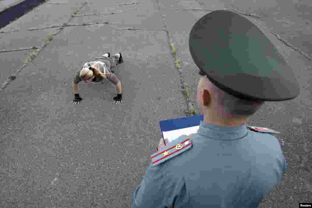 An officer looks at a candidate as she does push-ups during the selection process for a professional contract in the Russian army at a recruitment centre in the southern city of Stavropol on September 25. (REUTERS/Eduard Korniyenko)