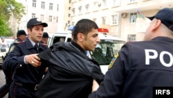 Police detain one of the young protesters in Baku.