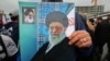 An Iranian holds up a poster showing a portrait of the country's Supreme Leader Ali Khamenei (C) with a small portrait in the corner showing Islamic Revolution founder Ayatollah Ruhollah Khomeini, during a ceremony celebrating the 40th anniversary.