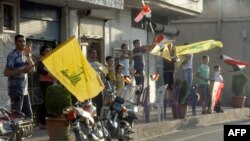 أهالي مدينة القصير السورية يلوحون بأعلام بلادهم وحزب الله اللبناني إحتفالاً بسيطرة القوات الحكومية على المدينة