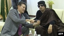 FIDE президенті Кирсан Илюмжинов (сол жақта) Ливияның сол кездегі президенті Муаммар Каддафимен бірге отыр. Триполи, 12 маусым 2011 жыл.
