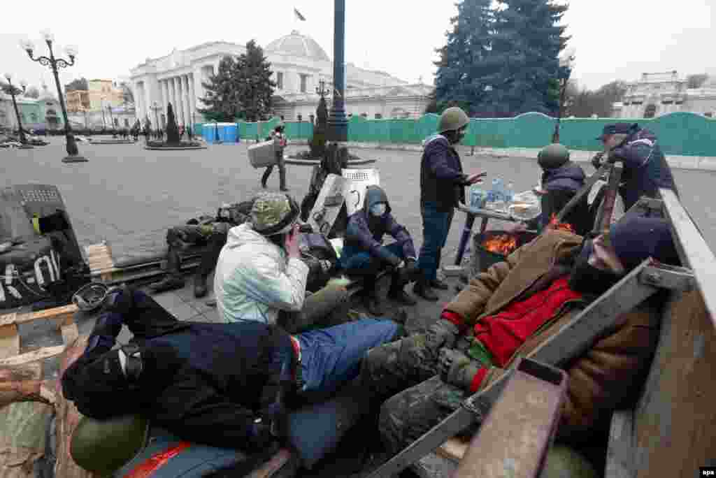Ukrainian protesters rest at a barricade.
