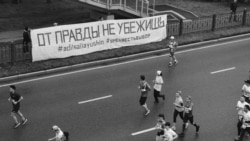 Участники марафона пробегают мимо баннера Тулесовой и Толымбекова, Алматы, 21 апреля 2019 года.