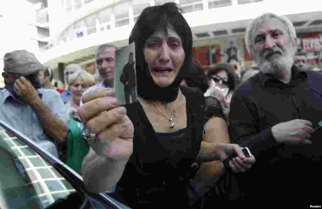 A Georgian woman holds a picture of her son, who she says became an invalid from injuries sustained while in prison, during a protest rally over videos of prison abuse in Tbilisi. (Reuters/David Mdzinarishvili)