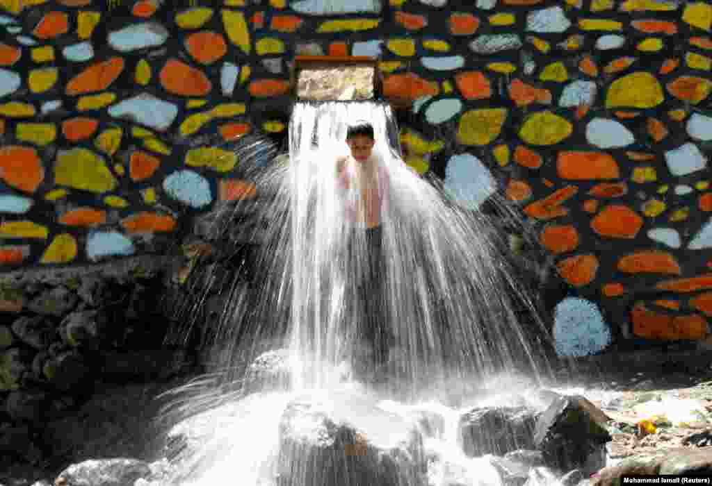 An Afghan boy cools off under a waterfall in Kabul&#39;s Paghman district. (Reuters/Mohammad Ismail)