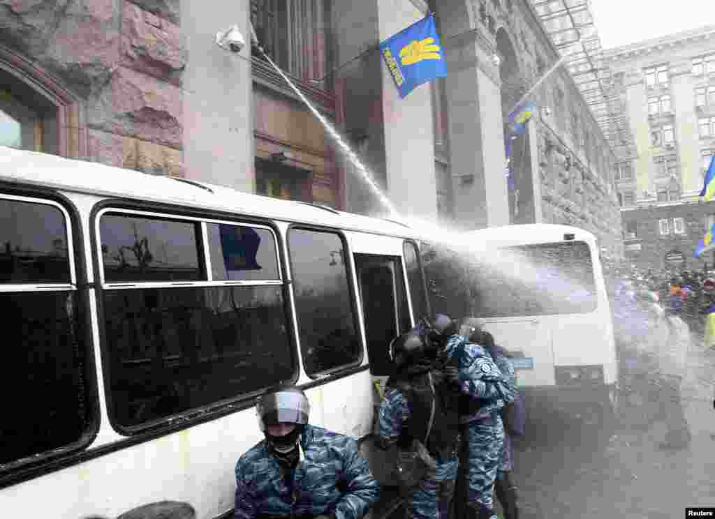 Ukrainian antigovernment protesters spray riot police with a water hose to prevent them from entering the City Hall, which they have occupied in Kyiv, on December 11. (Reuters/Valentin Ogirenko)