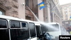 Occupiers of the Kyiv city hall building use a water hose to keep police at bay.