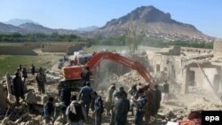 Afghan security forces inspect the site of a blast at a police arms depot in Kandahar on April 21. At least one person was killed and 15 injured.