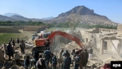 Afghan security forces inspect the site of a blast at a police arms depot in Kandahar on April 21.