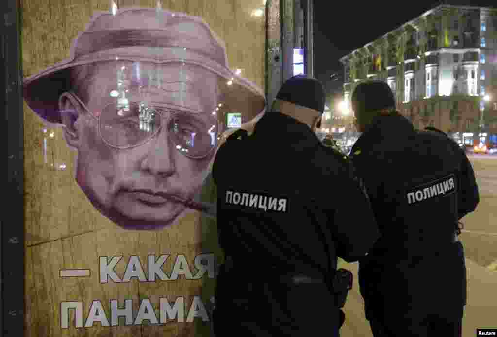 Russian police officers stand near a poster depicting Russian President Vladimir Putin and reading "Which Panama?" at a bus stop in Moscow on April 6. (Reuters/Sergei Karpukhin)