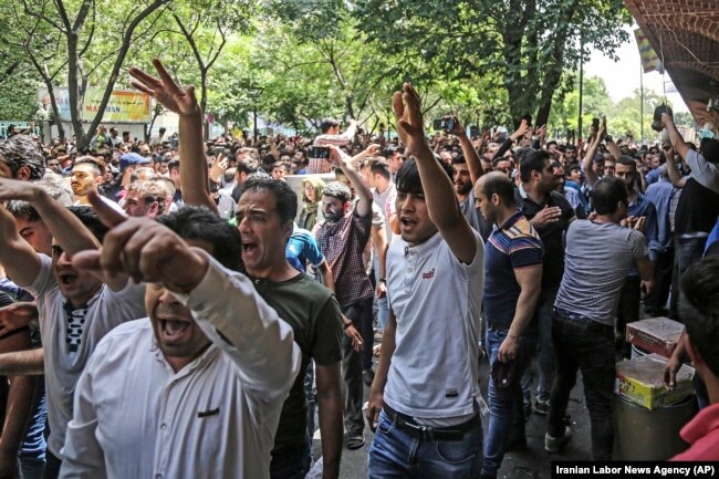 In this June 25, 2018 file photo, a group of protesters chant slogans at the old grand bazaar in Tehran, Iran, as the national currency loses value and inflation picks up.