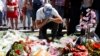 A man reacts near bouquets of flowers as people pay tribute near the scene where a truck ran into a crowd at high speed killing scores and injuring more who were celebrating the Bastille Day national holiday, in Nice, France, July 15, 2016. 