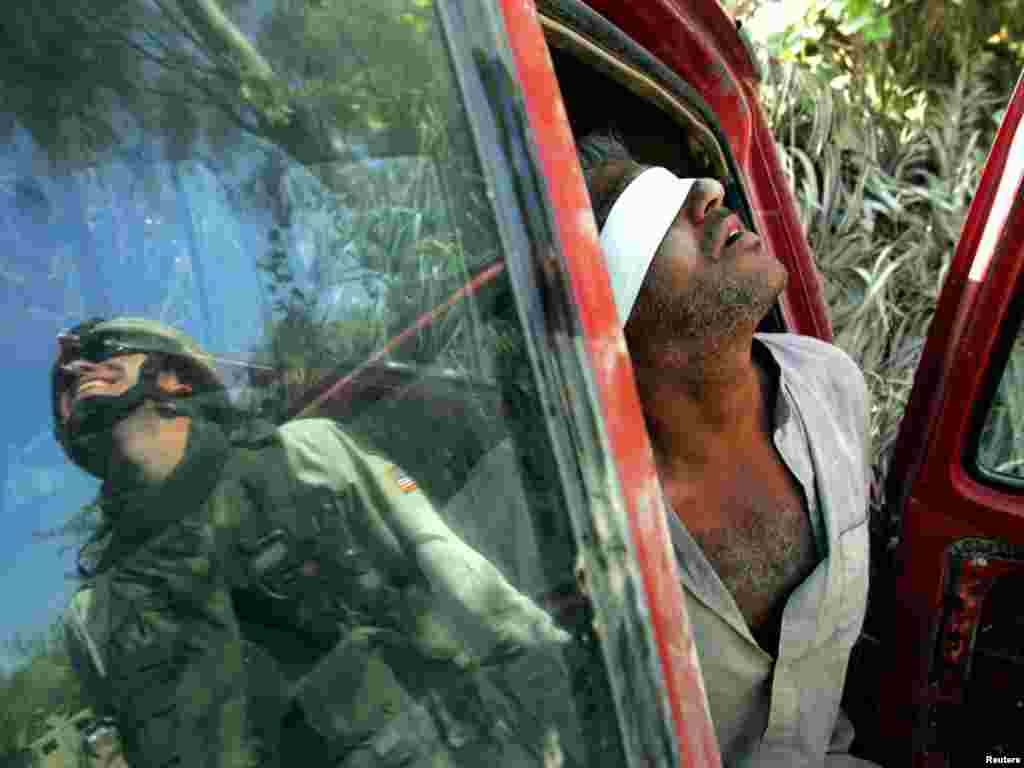 An Iraqi man suspected of having explosives in his car is held after being arrested by the U.S army near Baquba, Iraq, October 15, 2005. Iraqis headed to the polls in an historic referendum on Saturday, with up to 15 million eligible voters deciding on a controversial new post-Saddam Hussein constitution that its backers hope will unite the torn country. Amid intense security, including a ban on all traffic, voters flowed on foot to polling stations across Baghdad. REUTERS/Jorge Silva