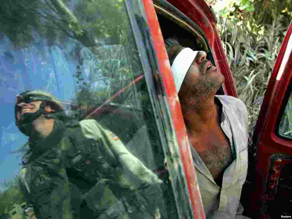 An Iraqi man suspected of having explosives in his car is held after being arrested by the U.S army near Baquba, Iraq, October 15, 2005. Iraqis headed to the polls in an historic referendum on Saturday, with up to 15 million eligible voters deciding on a controversial new post-Saddam Hussein constitution that its backers hope will unite the torn country. Amid intense security, including a ban on all traffic, voters flowed on foot to polling stations across Baghdad. REUTERS/Jorge Silva 