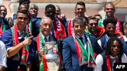 Кріштіану Роналду (л), Марселу Рібелу ді Соуса (2-й л) та члени й посадовці збірної Португалії під час святкувань у Лісабоні, 11 липня 2016 року