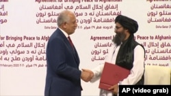 U.S. envoy Zalmay Khalilzad (left) and Mullah Abdul Ghani Baradar, the Taliban's top political leader, shake hands after signing the peace agreement in Doha on February 29, 2020.