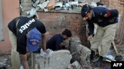 Pakistani police examine the site of a suicide bomb blast in Peshawar.