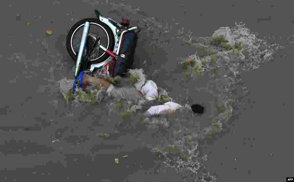 A Pakistani man falls off his motorbike into floodwaters following heavy rain in Lahore. (AFP/Arif Ali)