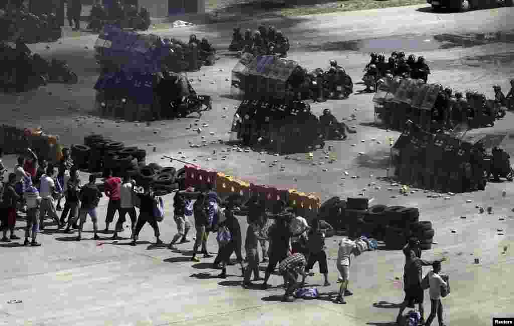 Mock rioters (left) throw fake bricks at police officers in riot gear during an antiterrorist drill in Beijing (Reuters/China Daily)