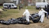 Men wearing protective gear exhume the bodies of civilians killed during the Russian occupation of Bucha, on the outskirts of Kyiv, on April 8, 2022.