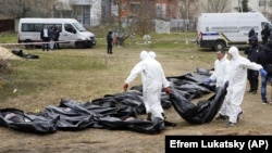 Men wearing protective gear exhume the bodies of civilians killed during the Russian occupation of Bucha, on the outskirts of Kyiv, on April 8, 2022.