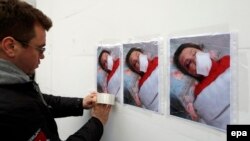 A protester hangs up pictures of journalist Tetyana Chornovol on a wall in front of the Interior Ministry building in Kyiv.