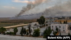 Smoke rises from the Syrian town of Tal Abyad in a photo taken from the Turkish side of the border.