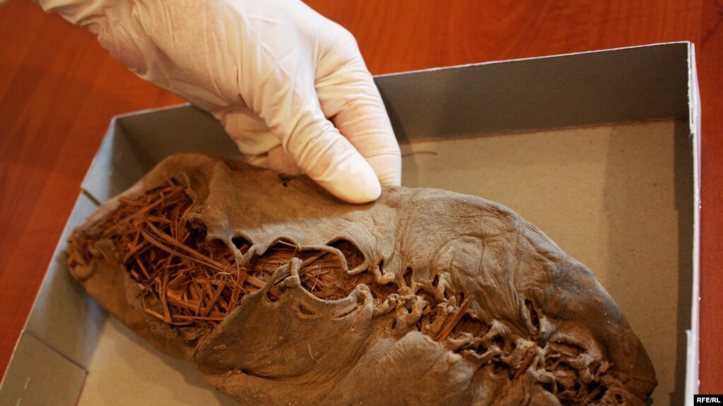 A researcher holds the ancient shoe at the Armenian Institute of Archaeology and Ethnography.