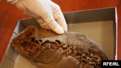 A researcher holds the ancient shoe at the Armenian Institute of Archaeology and Ethnography.