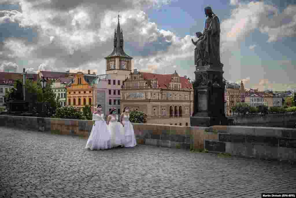 Models wearing protective face masks and wedding dresses walk on the Charles Bridge as they take part in a commercial shoot in Prague. (epa-EFE/Martin Divisek)