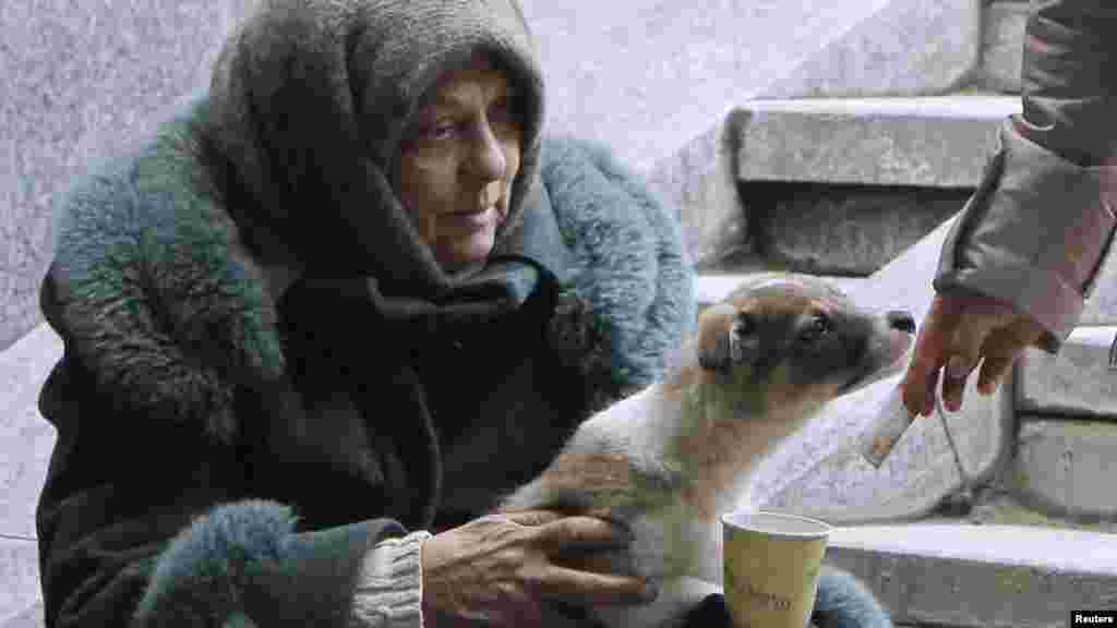 A woman with a dog begs for money in central Kyiv on February 29. (Reuters/Gleb Garanich)