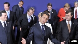 French President Nicolas Sarkozy gestures as he and other EU leaders leave a family photo at the start of the European Council summit in Brussels on June 17.