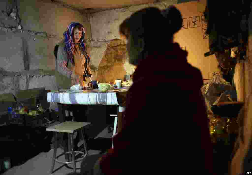 Жінка готує сніданок у підвалі-бомбосховищі власного будинку. Село Піски під Донецьком, 20 листопада 2014 року