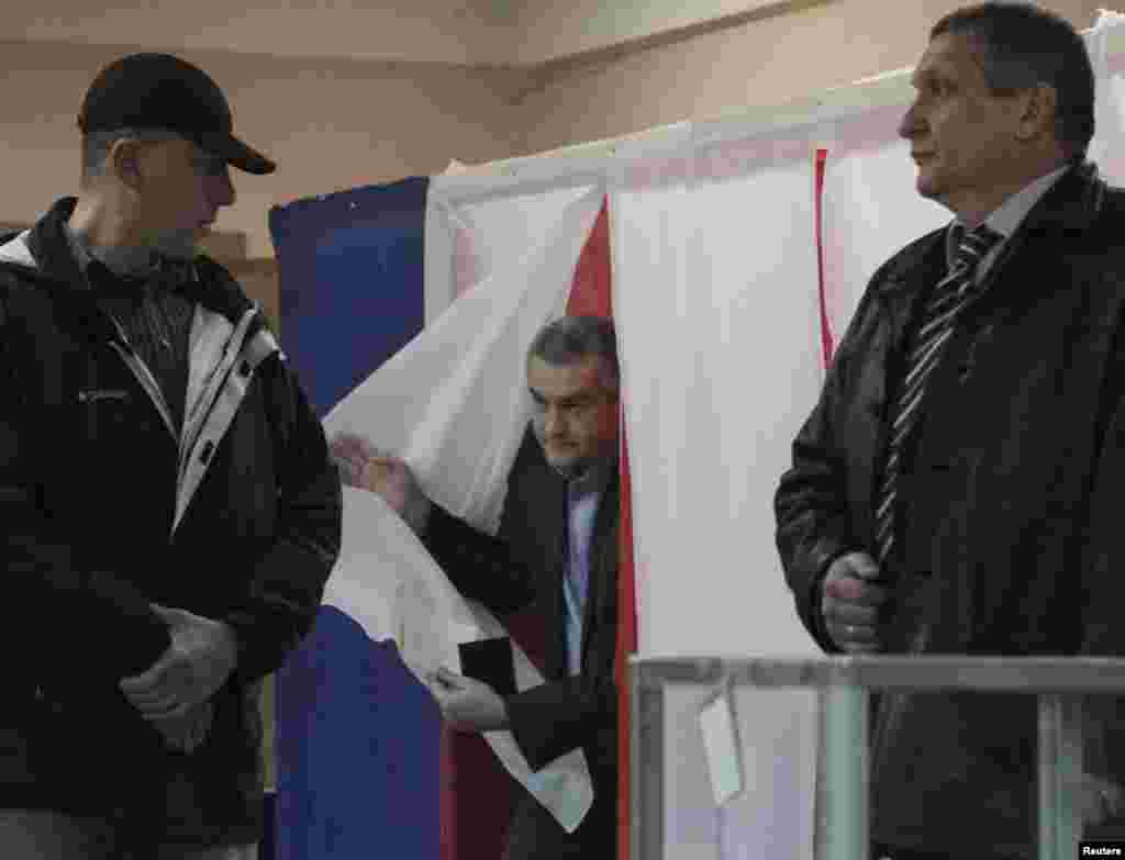 Crimean Prime Minister Sergei Aksyonov (center) leaves a voting booth to cast his ballot in Simferopol.