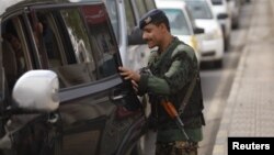 A Yemeni police trooper checks a car at a checkpoint on the road leading to Sanaa International Airport on August 6.