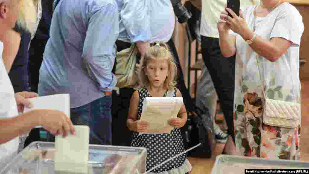 Voting is a family event in Ukraine. Many voters bring their children to the polling stations and let them drop the marked ballots in the boxes. (RFE/RL/Serhii Nuzhnenko)