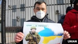 Плакат із зображенням президента Росії Володимира Путіна під час акції «Крим – це Україна» біля російського посольства в Києві, 16 березня 2020 року