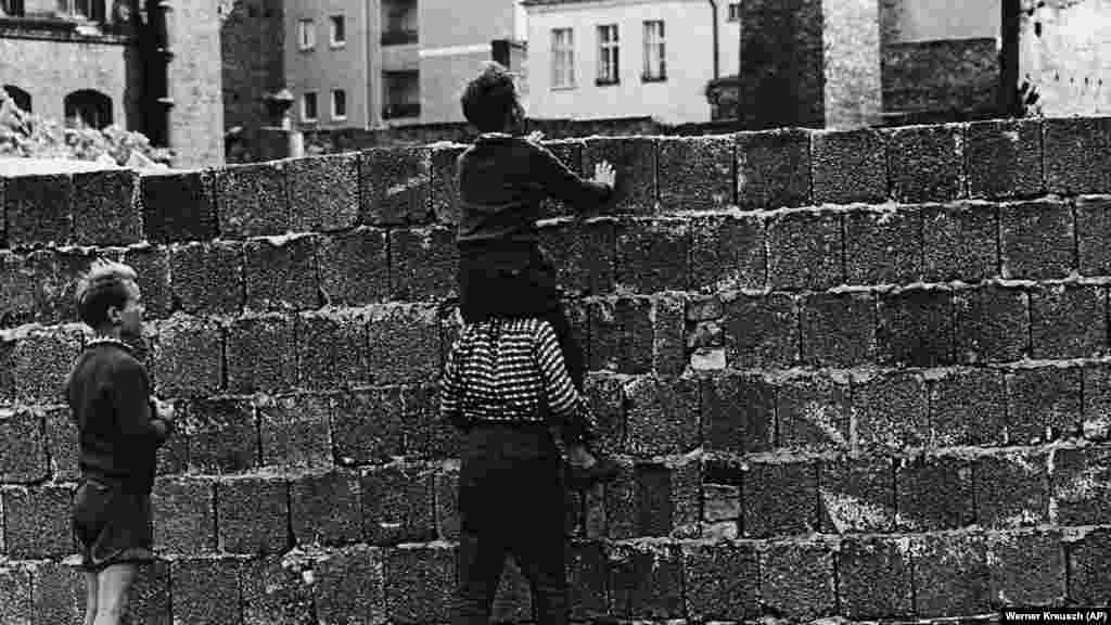 Egy kisfiú ül társa vállán, hogy átlásson a fal felett a keleti városrészre 1961. augusztus 23-án.