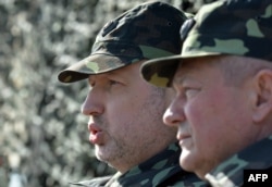 И.о. президента Украины Александр Турчинов (слева) и министр обороны Украины Игорь Тенюх принимают участие в военных учениях возле Киева, 14 марта 2014 года