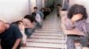 While covering their faces, Iranian youth who had been arrested in recent student protests, sit in a hallway of the Evin prison, in Tehran, Iran, Sunday, June 15, 2003. (AP Photo)